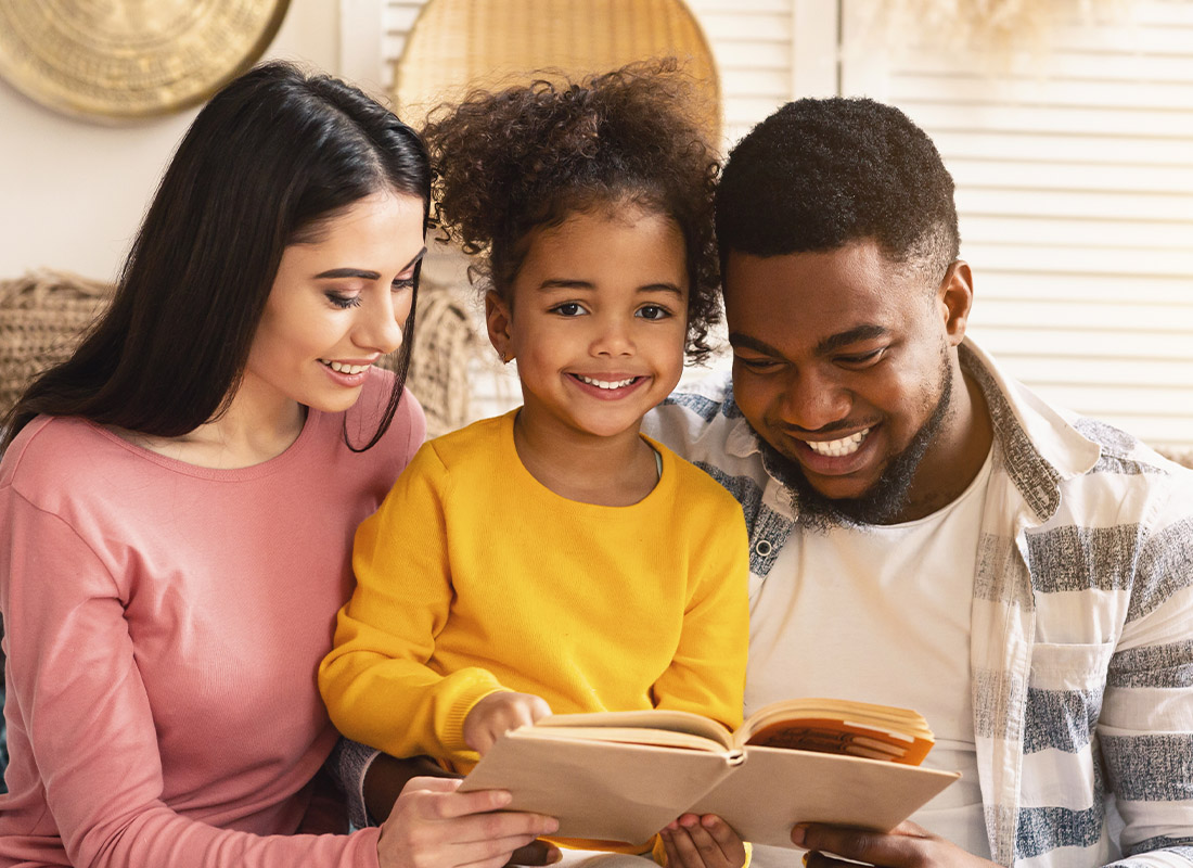 Life Insurance - Happy Family at Home and Reading While Sitting on the Living Room Sofa